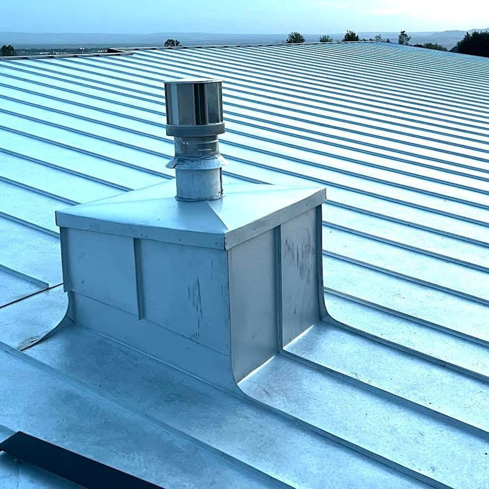 Metal roof with ventilation pipe, highlighting sleek design and durable material.