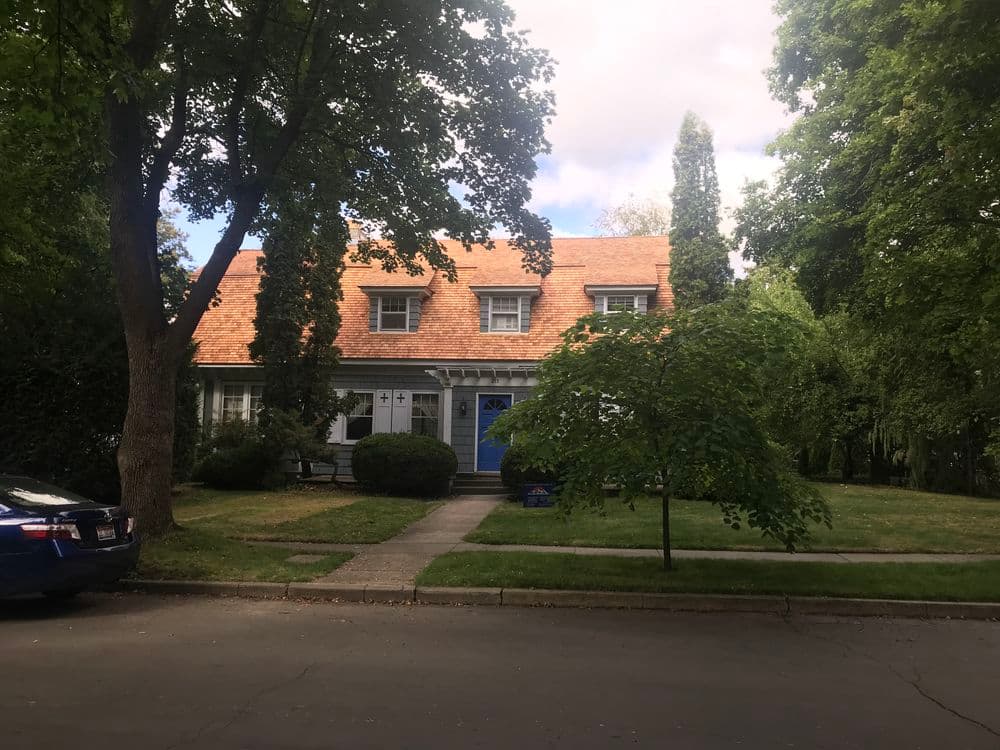 Two-story house with an orange roof, blue door, and landscaped front yard.